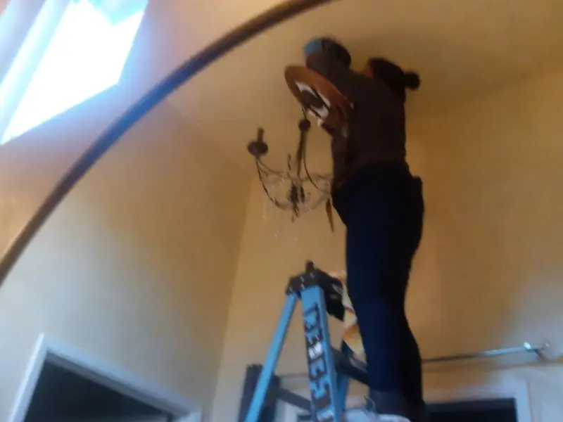 Electrician installing a chandelier in a Gilmer residence